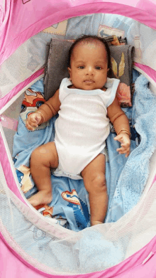 a baby is laying in a pink crib with a blanket that says disney cars on it