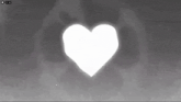 a white heart is glowing in the dark against a gray background .