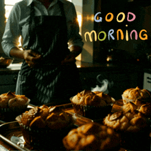 a man in an apron stands in front of a tray of muffins with the words " good morning " written above him