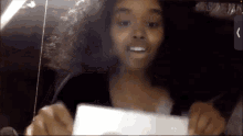 a girl with curly hair is holding a piece of paper and smiling