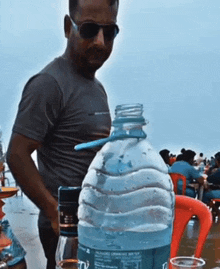 a man is standing next to a bottle of water with a straw sticking out of it