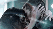 a man and a woman are hugging and kissing behind a glass .