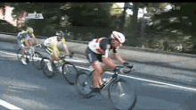 a group of cyclists are riding down a road with the number 21 on the side of the road .