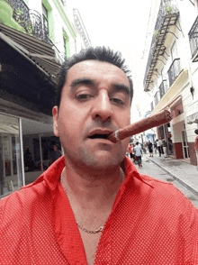 a man wearing a red shirt is smoking a cigar