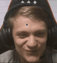 a man wearing headphones has a sticker on his forehead with a hand pointing to it