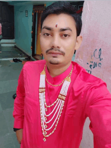 a man wearing a red shirt and a pearl necklace poses for a picture