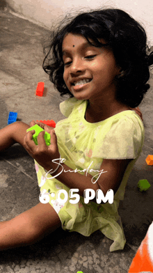 a little girl is playing with toys and the time is 6:05 pm