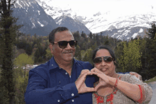 a man and woman are making a heart with their hands