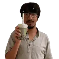 a man wearing glasses is holding a cup of bubble tea with a straw