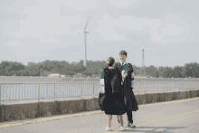 a man and a woman in graduation gowns are holding hands