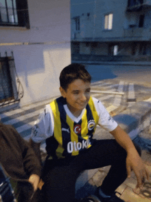 a boy wearing a yellow and black shirt with the word otok on it