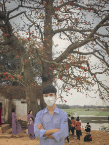 a boy wearing a face mask stands in front of a tree with red flowers