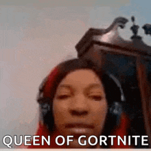 a woman wearing headphones is making a funny face and says queen of gortnite .