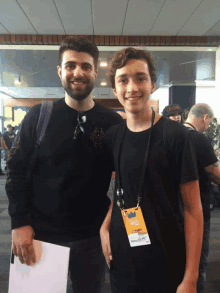 two men are posing for a picture and one has a lanyard around his neck with a name tag that says ' chris '