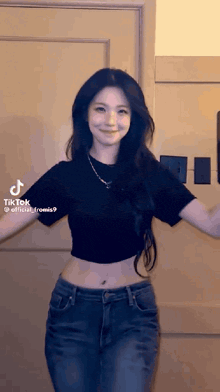 a woman in a black crop top and blue jeans is dancing .