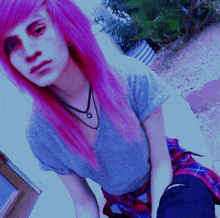 a girl with pink hair is wearing a gray shirt and a plaid skirt