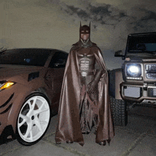 a man in a batman costume is standing next to a car