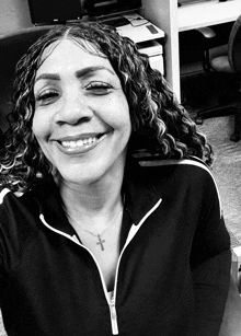 a black and white photo of a woman smiling with a cross necklace