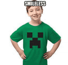 a young boy wearing a green t-shirt with a creeper on it is smiling .