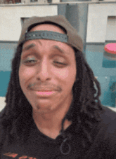a man with dreadlocks is wearing a hat