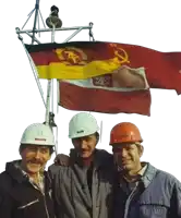 three men wearing hard hats are posing in front of a flag