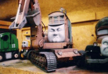 a toy excavator has a face on it and the number 12 on the back of it