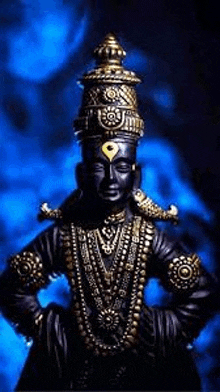 a black and gold statue of a deity with a crown on his head and a blue background .