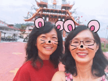 two women are posing for a picture in front of a building with chinese characters on it