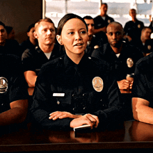 a group of police officers are sitting at a table and one of them has a name tag that says ' open ' on it