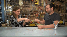 a man and a woman are holding hands in front of a wall of tools including a yellow dewalt tool