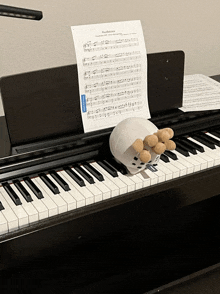 a stuffed animal sits on top of a piano keyboard with sheet music on it