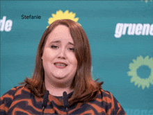 a woman stands in front of a green background with the name stefanie below her