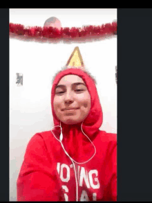 a woman wearing a red hoodie and a party hat is smiling for the camera