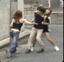 a man and two women are standing on a sidewalk