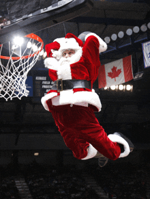 a man dressed as santa claus is jumping over a basketball hoop