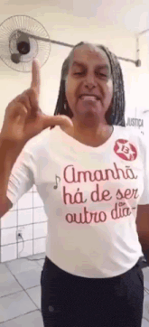 a woman wearing a t-shirt that says amanha ha de ser outro dia is pointing up .