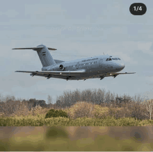 a gray airplane is flying over a field with the number 1/4 on the bottom