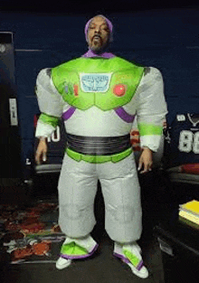 a man in a toy story buzz lightyear inflatable costume is standing in a room .