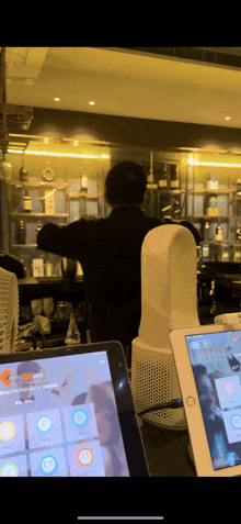 a man stands behind a counter with a tablet in front of him that says ' a ' on it