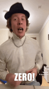 a man wearing a hat and a turtleneck has the word zero on his shirt