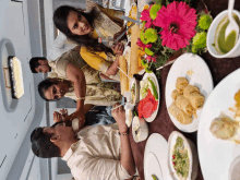 a group of people sit at a table with plates of food