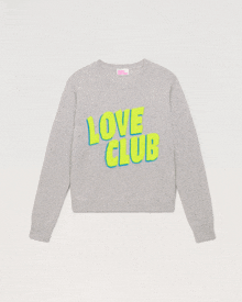 a grey sweater that says love club in neon yellow