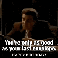 a man in a suit and tie is sitting at a desk with a birthday message .