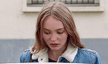 a young woman wearing a denim jacket is looking down