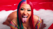 a woman with red hair and rainbow makeup is sticking her tongue out .