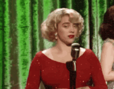 a woman in a red dress is singing into a microphone on stage .