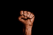 a close up of a person 's fist in the air on a black background .