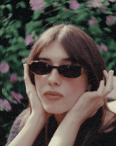 a woman wearing sunglasses holds her head with her hands