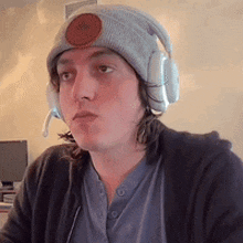 a man wearing headphones and a beanie is looking at the camera