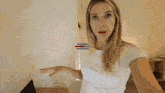 a woman in a white shirt is standing in a bedroom with a watermark that says ' ariel ' on it